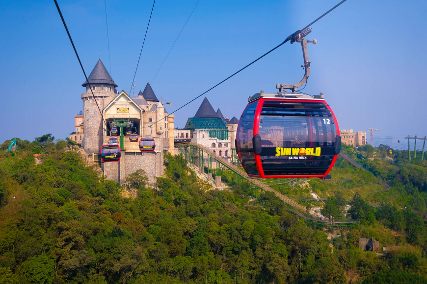 Cable car cabin on L’Indochine line with clouds and jungle landscape below
