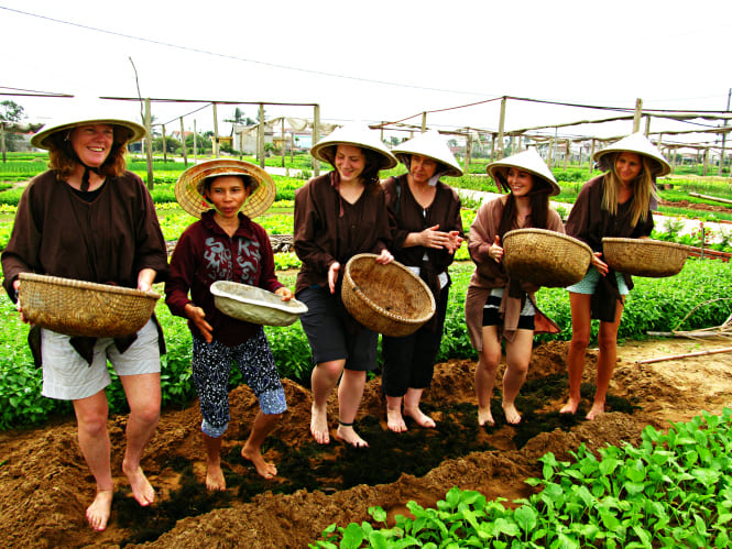 Foreigner in Tra Que Village learning traditional farming by digging soil and watering fresh herbs