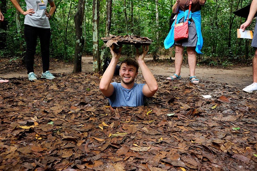 A tourist emerges from a hidden entrance at the Củ Chi Tunnels