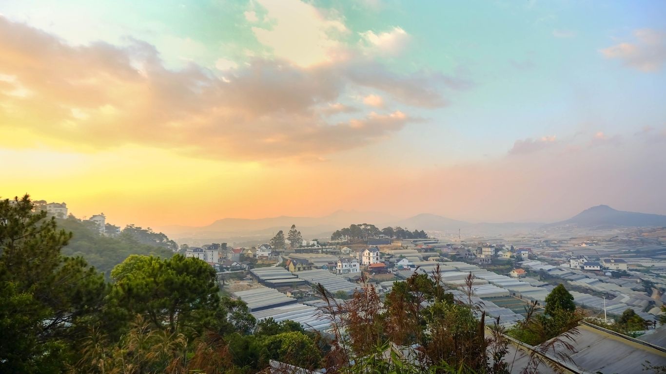 Da Lat city at sunrise with greenhouses and pine trees under colorful sky