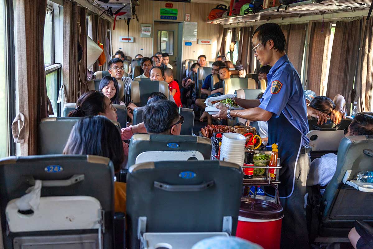 Food vendors walk the aisles with drinks and quick meals on Vietnam's railway