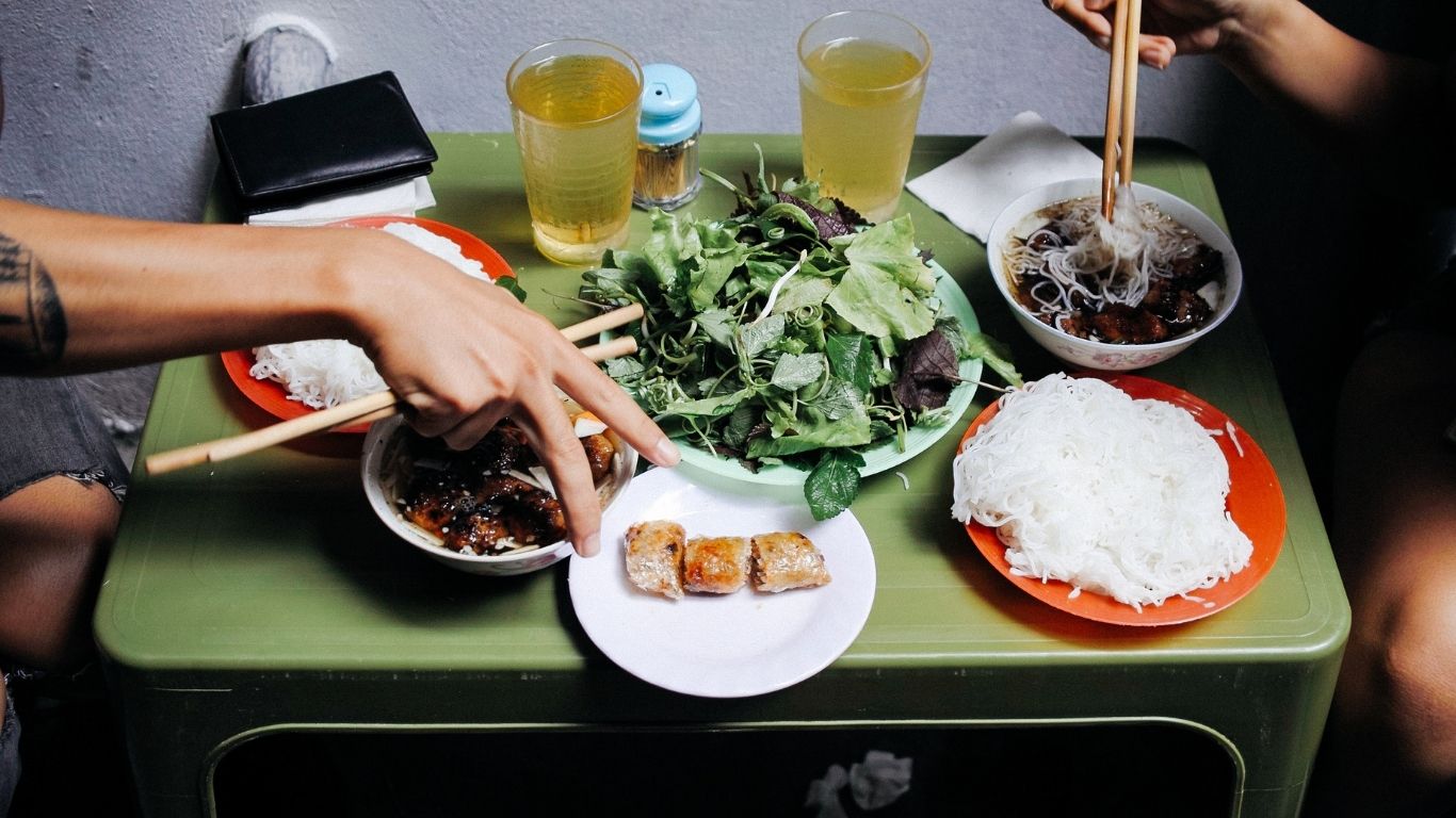 Enjoy an authentic Hanoi meal with bún chả and nem rán, served with herbs and dipping sauce