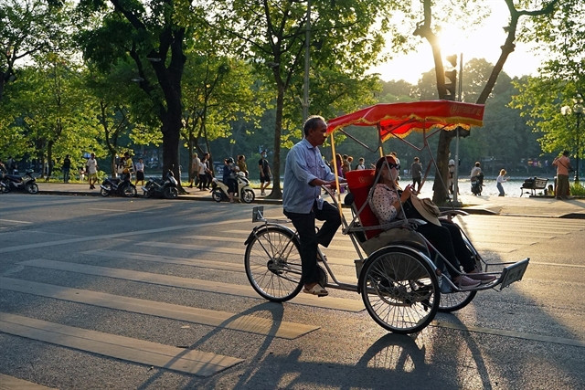 Cyclo carrying tourists through the bustling streets of Hanoi Old Quarter