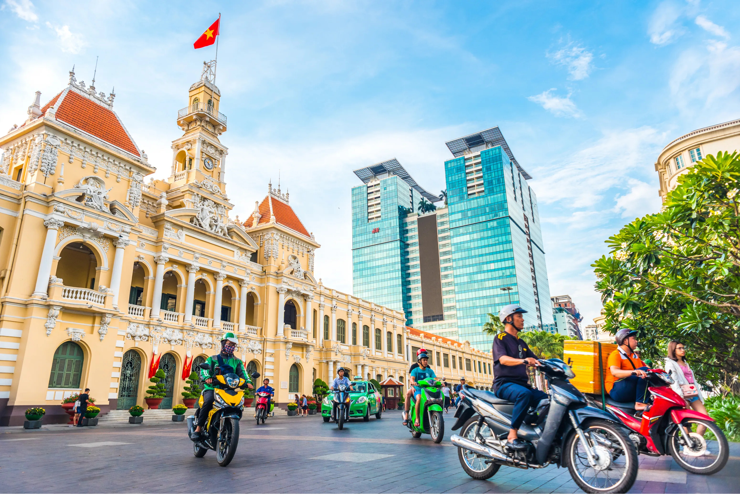 Bustling street scene in Ho Chi Minh City with motorbikes, local vendors, and tall buildings in the background