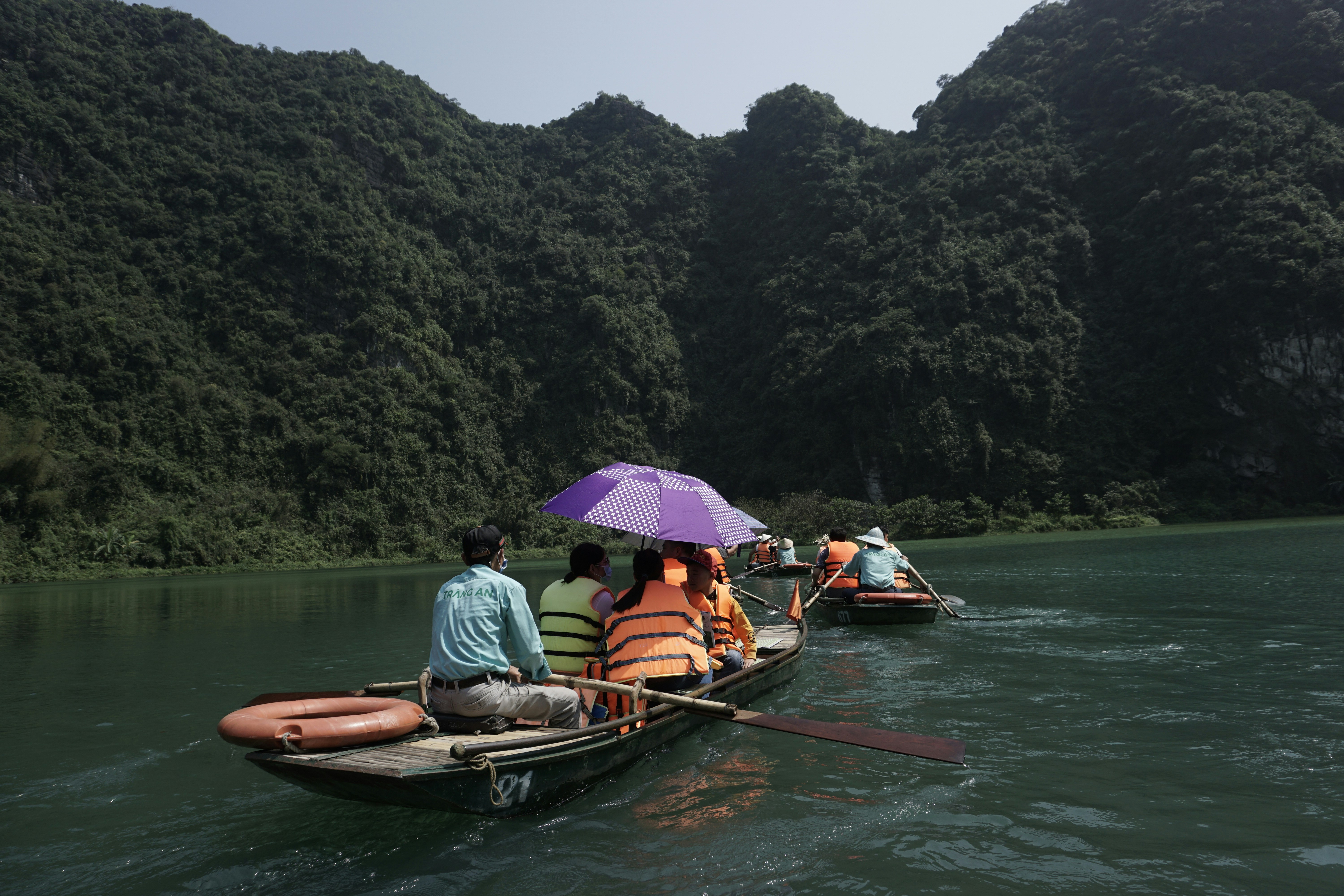 Tourist on a sampan boat ride through river and limestone mountains in Ninh Bình