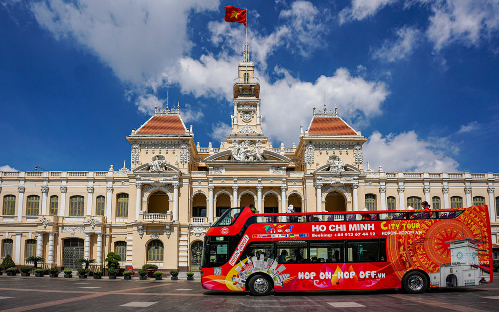 Tourists ride the red Hop-on Hop-off bus past Saigon’s iconic landmarks